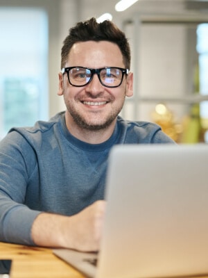E-commerce Manager man zit achter zijn laptop en kijkt in de camera